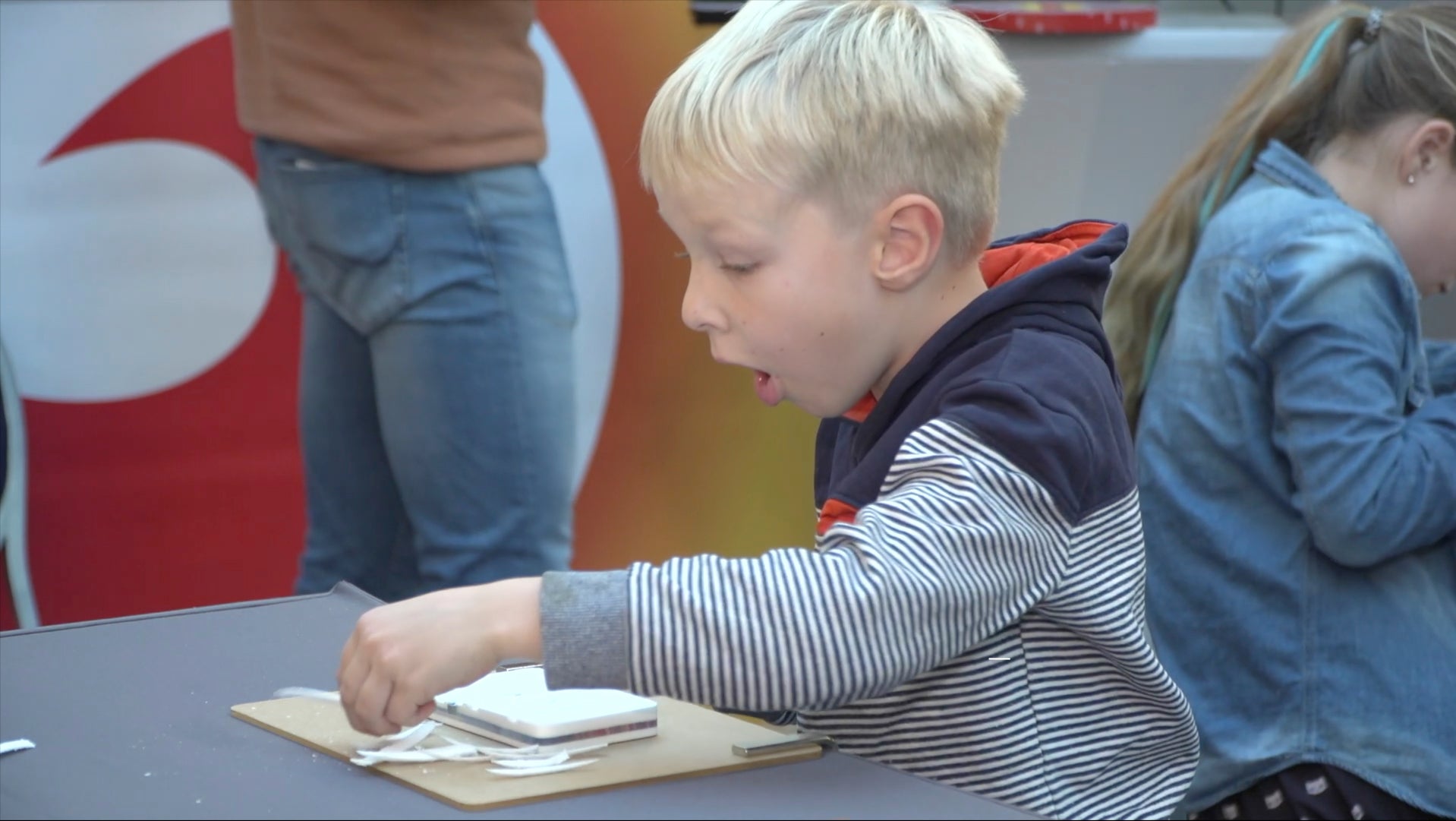Video laden: Das Video zeigt Ausschnitte von der Nacht der Wissenschaft in Kiel, bei der Kinder Schnitzen nach Farben ausprobieren. Sie sind konzentriert und mit Begeisterung bei der Sache.